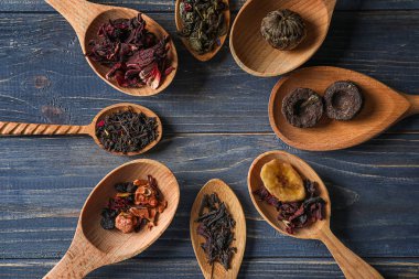 Kaşık ile farklı tip-in kuru çay yaprakları üzerinde ahşap arka plan