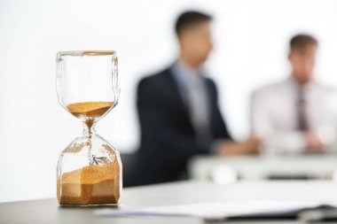 Kum saati ve arka plan üzerinde bulanık insanlar. Zaman yönetimi kavramı