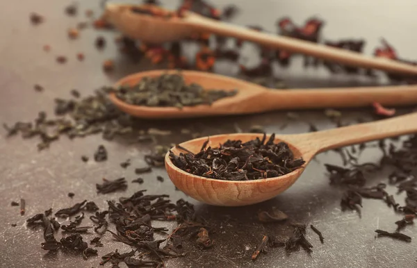 Colher com folhas secas de chá preto na mesa — Fotografia de Stock
