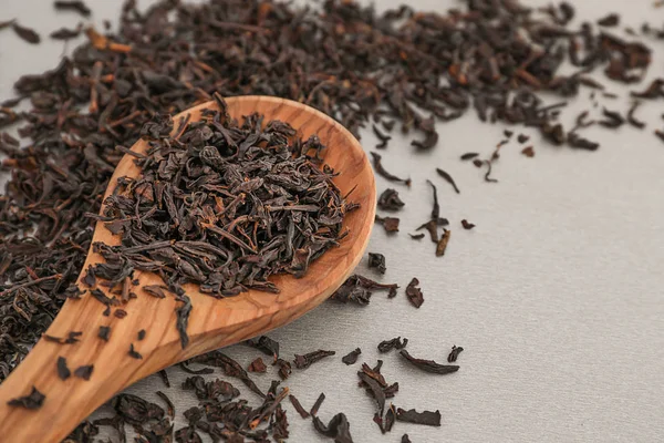Sked med torr svart te blad på grå bakgrund — Stockfoto