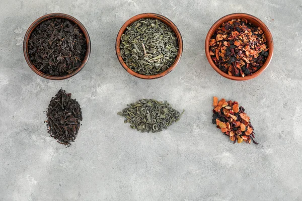 Verschillende soorten droge thee bladeren op grijze achtergrond — Stockfoto