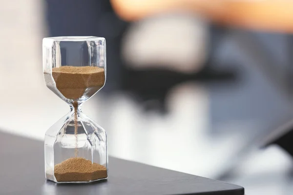 Ampulheta na mesa contra fundo desfocado. Conceito de gestão do tempo — Fotografia de Stock