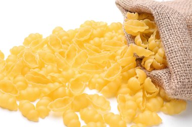 Beyaz arka planda, closeup dağınık pişmemiş makarna ile çuval