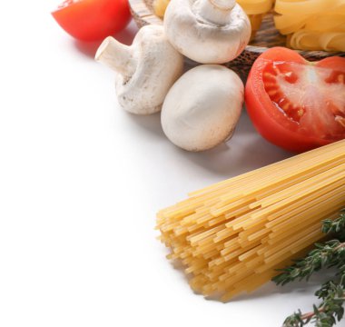 Beyaz arka planda pişmemiş makarna ve sebzeler