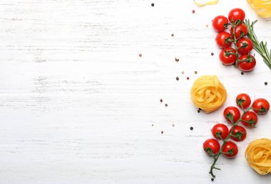 Pişmemiş makarna ve domates ahşap arka plan üzerinde