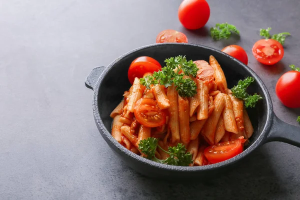 Pan with tasty penne pasta in tomato sauce on table — Stock Photo, Image