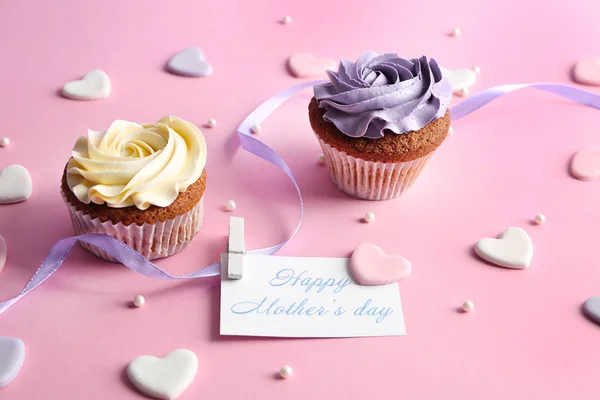 Sabrosos cupcakes y tarjeta con palabras FELIZ DÍA DE LA MADRE en la mesa — Foto de Stock