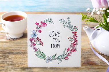 Kart kelimelerle aşk anne, fincan çay ve masaya çiçek sen. Anneler günü kutlama