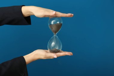 Renk arka plan üzerinde kum saati tutan kadın. Zaman yönetimi kavramı