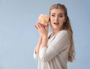 Renkli arka planda hediye kutusu olan güzel genç bir kadın.