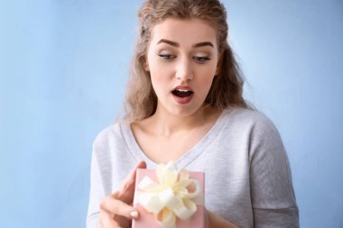 Renkli arka planda hediye kutusu olan güzel genç bir kadın.