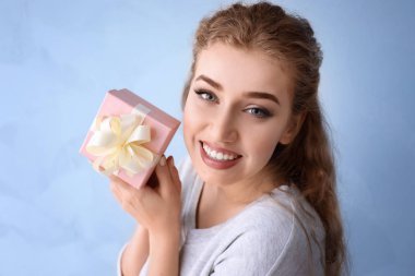 Renkli arka planda hediye kutusu olan güzel genç bir kadın.