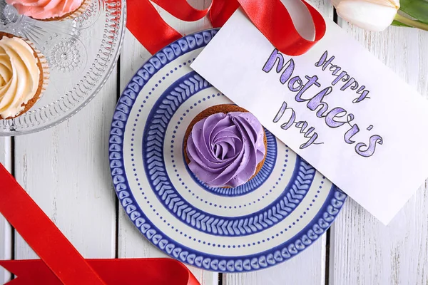 Tasty cupcake and card with words HAPPY MOTHER'S DAY on serving board — Stock Photo, Image
