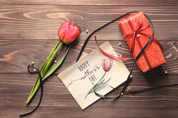 Kort med ord glad mors dag, tulip och gåva rutan på trä bakgrund, ovanifrån — Stockfoto