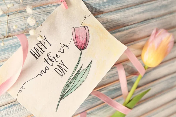 Kort med ord glad mors dag och blommor på trä bakgrund, närbild — Stockfoto
