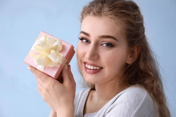 Gyönyörű fiatal nő ajándék doboz színes háttér — Stock Fotó