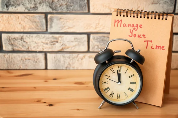 Relógio despertador e notebook com frase "Gerencie seu tempo" na mesa de madeira — Fotografia de Stock