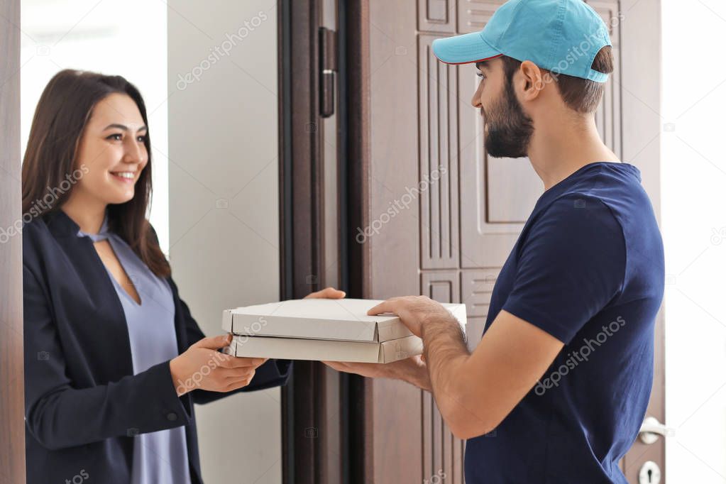 Young woman receiving cardboard pizza boxes from delivery man