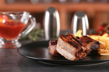 Plaka lezzetli ızgara kaburga ve masada patates kızartması ile