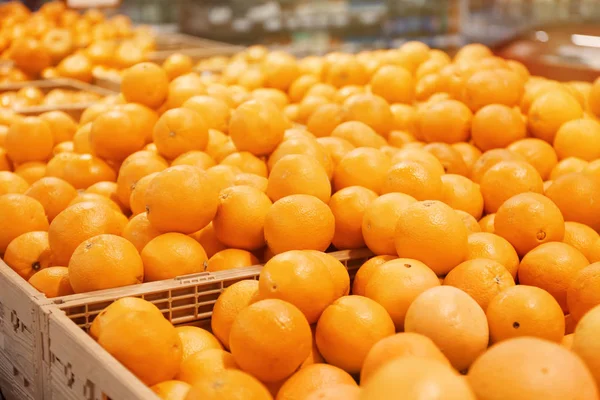 Muchas naranjas maduras en cajas de plástico en el mostrador del mercado. Cítricos — Foto de Stock