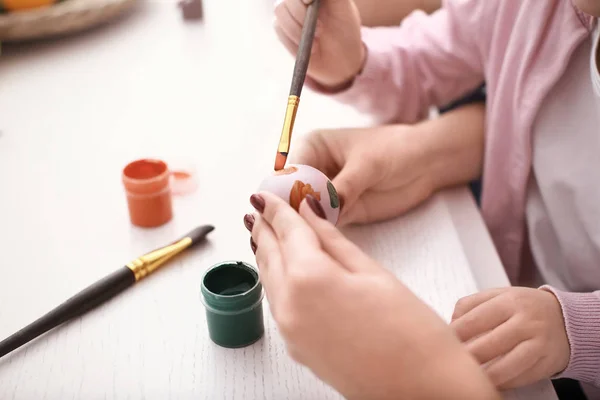 Mother painting Easter egg with her daughter at table, closeup — Stock Photo, Image