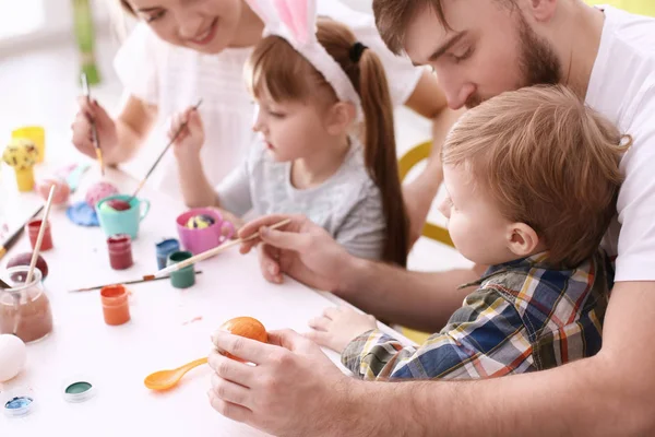 Family painting Easter eggs together at table