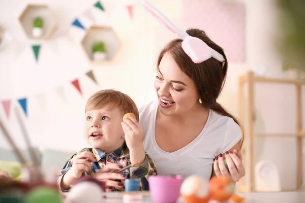 Anne çocuğunu masada Paskalya yumurta boyamak — Stok fotoğraf
