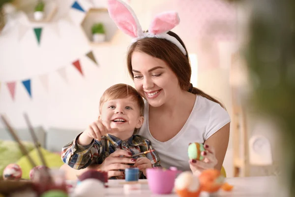 Mother painting Easter eggs with her child at table — Stock Photo, Image