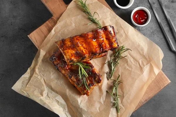 Delicious grilled ribs with rosemary on parchment — Stock Photo, Image