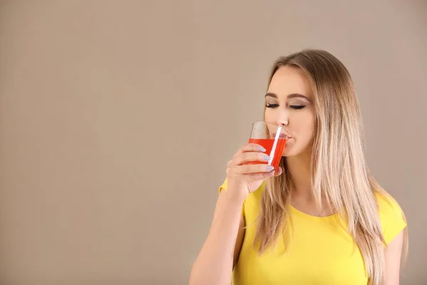 Beautiful young woman drinking citrus juice on color background — Stock Photo, Image