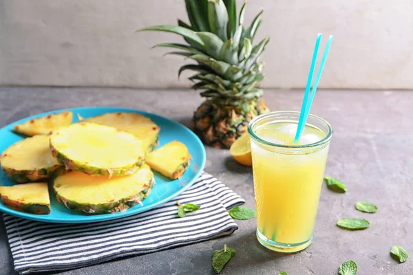 Plate with sliced pineapple and glass of fresh juice on table — Stock Photo, Image