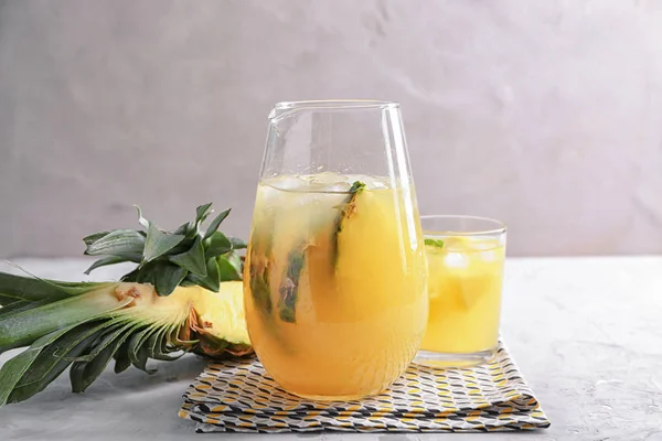 Jug and glass with tasty fresh pineapple juice on table — Stock Photo, Image