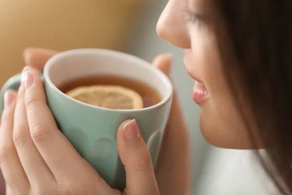 Mujer joven con taza de té caliente en casa, primer plano — Foto de Stock