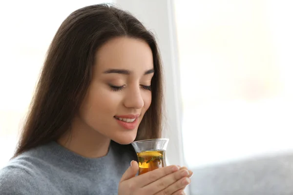 Beautiful young woman with cup of hot tea near window at home — Stock Photo, Image