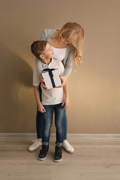 Portrait of cute little boy and his mother with gift box indoors — Stock Photo, Image