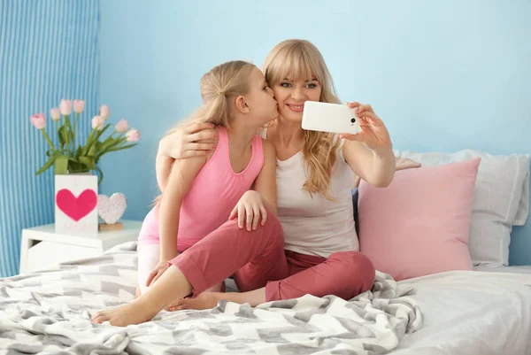 Schattig klein meisje en haar moeder nemen selfie in slaapkamer — Stockfoto