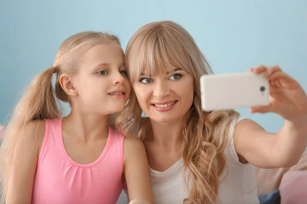 Ładna dziewczynka i jej matka biorąc selfie w domu — Zdjęcie stockowe