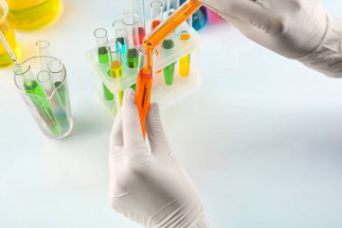 Tablo, closeup yakınındaki tüp içine portakal sıvı dökme laboratuar işçisi