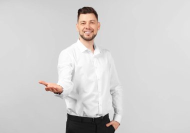 Bir şey gri arka plan üzerinde tutan genç işadamı