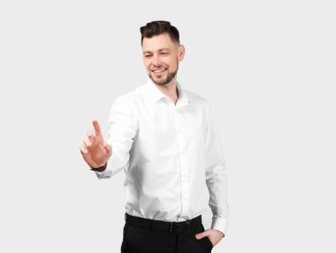 Genç işadamı sanal ekran gri arka plan üzerinde kullanma