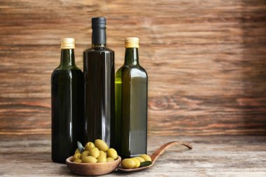 Zeytin ve yağı şişelerde ahşap arka plan üzerinde kompozisyonu