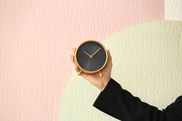 Женщина держит будильник на цветном фоне. Концепция управления временем — стоковое фото