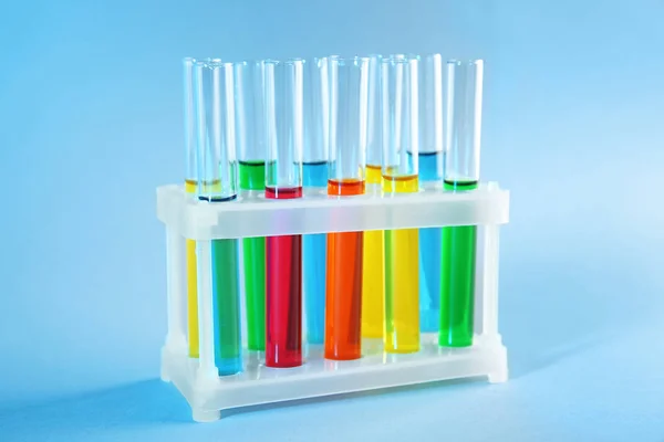 Test tubes with colorful liquids in holder on color background — Stock Photo, Image