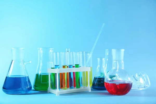 Vetreria chimica con campioni colorati su sfondo colore — Foto Stock