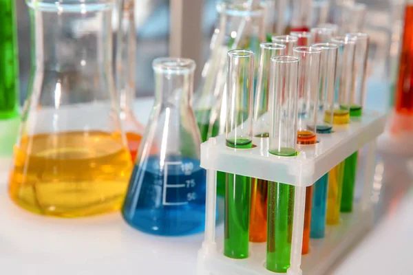 Tubos de ensaio com líquidos coloridos em suporte na mesa — Fotografia de Stock