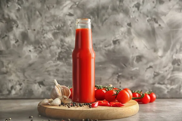 Flasche mit leckerer Tomatensauce und Gemüse auf dem Tisch — Stockfoto