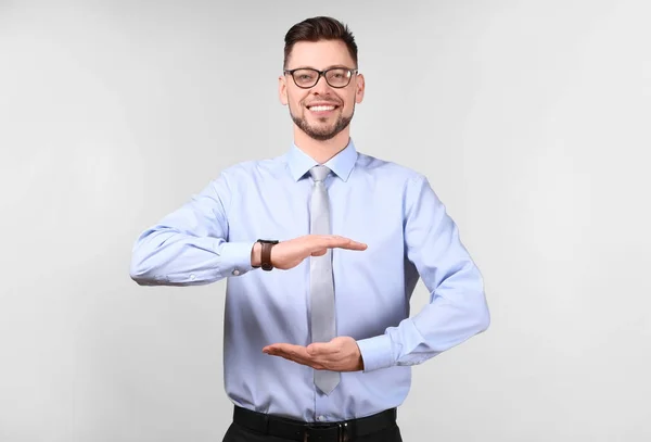 Young businessman holding something on gray background — Stock Photo, Image