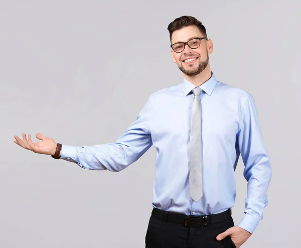 Joven empresario sosteniendo algo sobre fondo gris —  Fotos de Stock