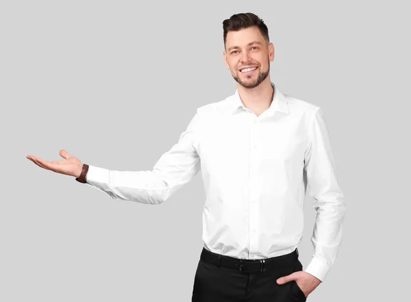 Young businessman holding something on gray background — Stock Photo, Image
