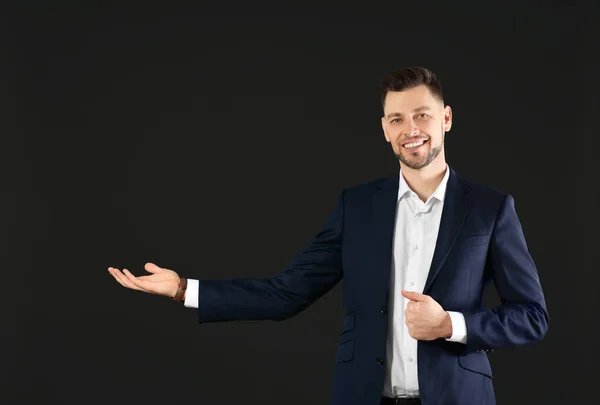 Young businessman holding something on black background — Stock Photo, Image